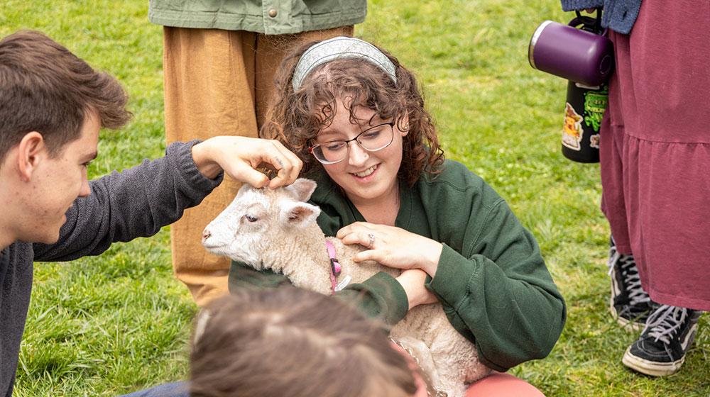 two students petting a goat